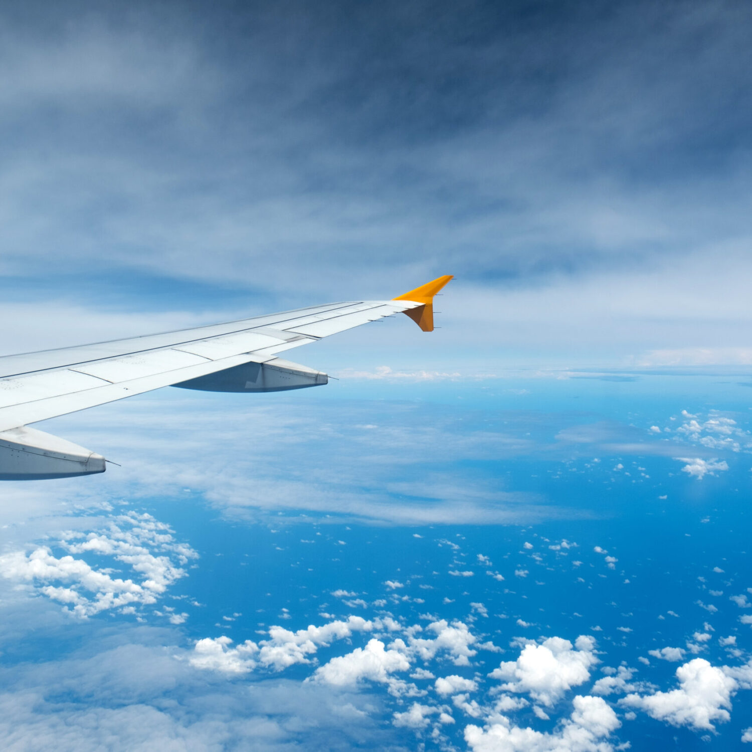 Wing of an airplane flying above the clouds see through the window. Business concept.